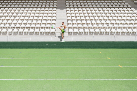 Athlete practicing warm up exercise at sports field on sunny day