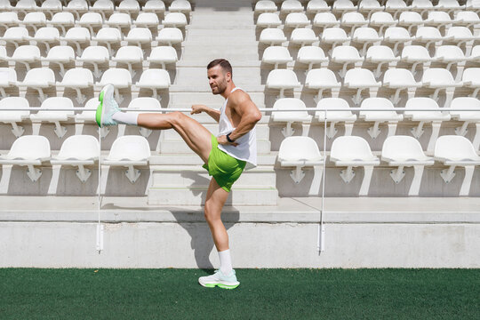 Man practicing warm up exercise at sports field on sunny day