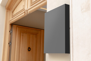 Wall-mounted black signboard on a textured wall, ideal for businesses to display their brand logo or promotional content. Black signage mockup.