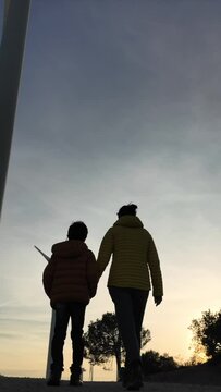 Mother with son walk through a renewable energy wind farm during the sunset. Silhouette of people and wind turbine. Concept sustainability, climate change, saving the earth. green energy and zero emis