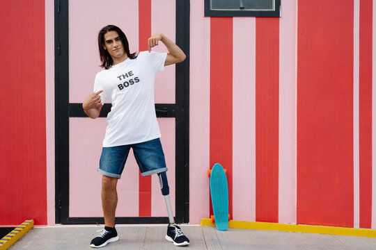 Man pointing himself while standing against multi colored wall