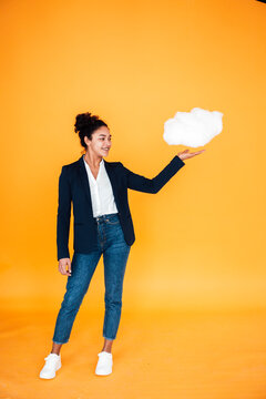 Happy businesswoman with cloud standing against yellow background