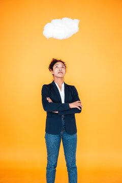 Businesswoman looking at cloud levitating over her against yellow background