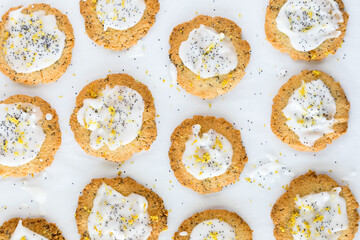 Top down view of homemade lemon poppyseed cookies on white parchment paper.