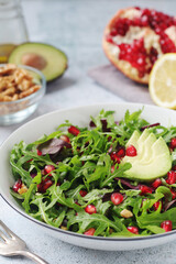 A plate with green rocket salad with pomegranate and avocado