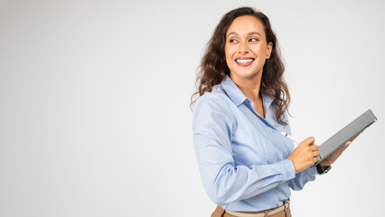 A joyful young woman with curly hair, wearing glasses, a blue shirt, and beige trousers