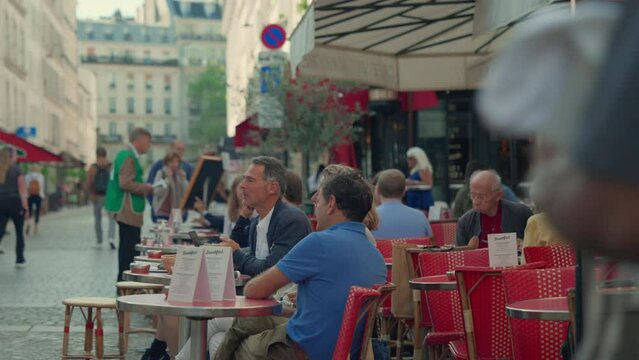 Parisians sitting at the tables of a street cafe in Paris