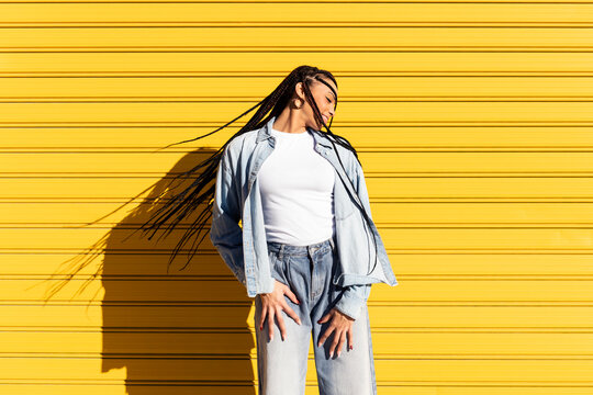 Smiling young woman with braided hair in front of corrugated shutter