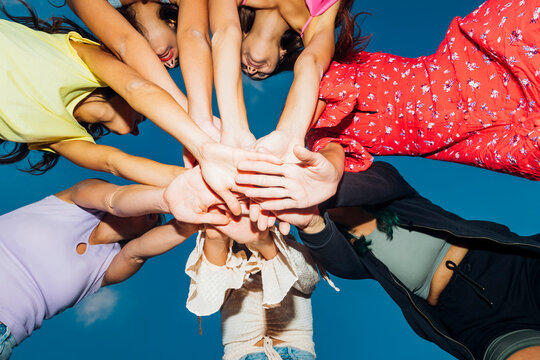 Female friends stacking hands at dusk