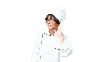 Young caucasian chef  woman over isolated chroma key background listening to something by putting hand on the ear