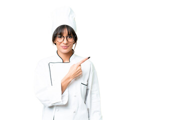 Young caucasian chef  woman over isolated chroma key background pointing to the side to present a...