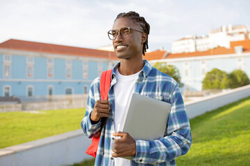 African American Student Guy Holds Laptop Standing With Backpack Outdoor