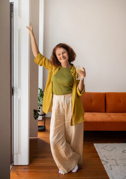 Radiant Senior Lady With Glass Of Wine In Hand Posing At Home