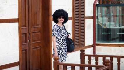 Young woman with black curly hair leaves home work.