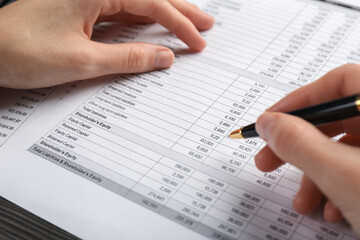 Woman working with accounting documents at table, closeup