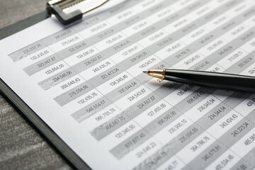 Clipboard with accounting document and pen on table, closeup