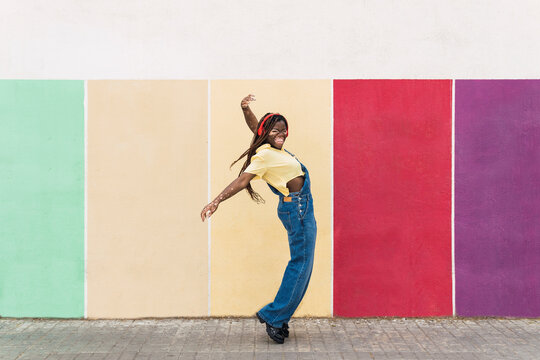 Happy woman dancing in front of multi colored wall