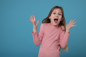 Portrait of surprised girl on light blue background