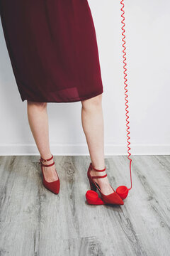 Woman crushing red telephone receiver with red heels