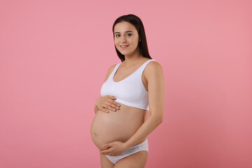 Beautiful pregnant woman in stylish comfortable underwear on pink background