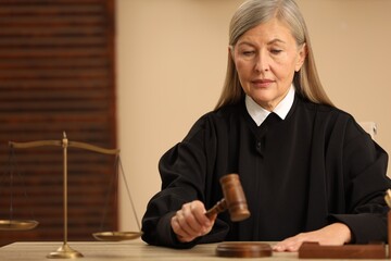 Judge striking mallet at wooden table indoors