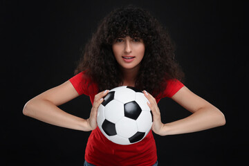 Fan holding soccer ball on black background