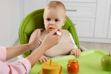 Mother feeding her cute little baby with healthy food at home