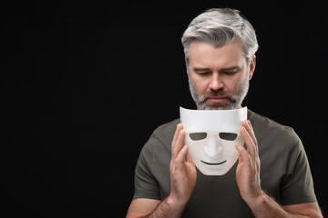 Multiple personality concept. Man with mask on black background. Space for text