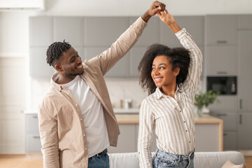 Cheerful black young couple dancing having fun at modern home