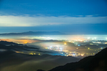Creating a glazed halo of light from the clouds and the lights of the village. Warm winter mountain scenery in northern Taiwan, Shuangxi Buyanting Pavilion.