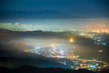 Creating a glazed halo of light from the clouds and the lights of the village. Warm winter mountain...
