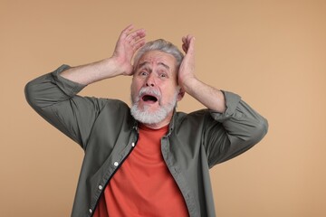 Portrait of surprised senior man on beige background