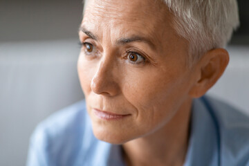 Cropped headshot of attractive senior woman looking aside indoor