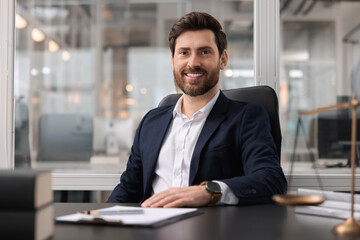 Fototapeta premium Portrait of smiling lawyer at table in office