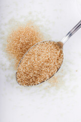 Brown sugar in silver spoon on white background