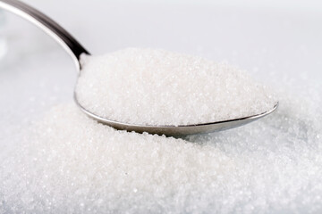  White sugar in silver spoon on white background