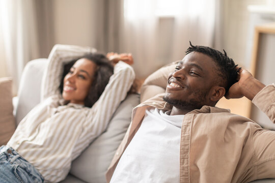 Millennial Black Couple Leaning Back On Sofa Relaxing At Home