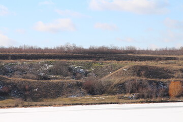 A landscape with a dirt hill and trees in the background
