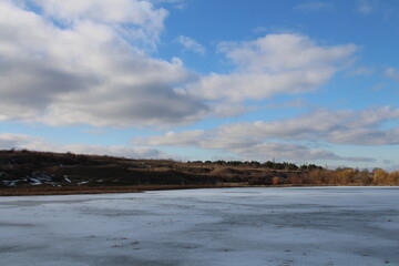 A snowy field with trees and blue sky