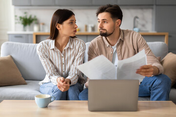 Worried couple reviewing documents with laptop