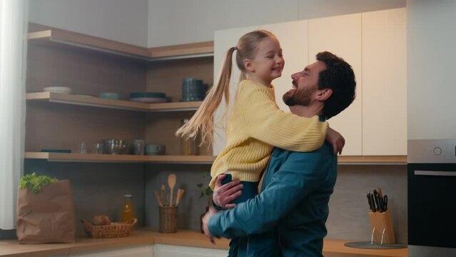 Caucasian family single dad father lift child in his arms up rise little kid daughter spinning rotate touch with noses love affectionate at kitchen home after cooking food cook salad bonding childcare