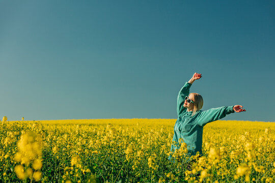Carefree woman with arms raised standing in rapeseed field