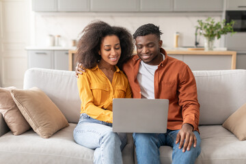 African American couple watching movie on laptop in living room