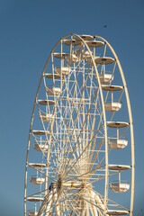 Big, tall white Ferris wheel. Modern ferris wheel at carnival with blue sky