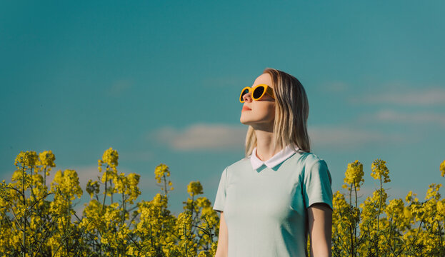 Blond woman wearing sunglasses in rapeseed field