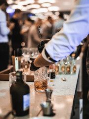 Expert barman is making cocktail at business banquet event in hotel conference center. Blurred...