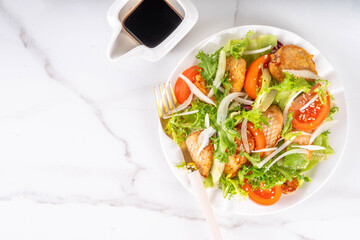 Healthy vegetable green salad with grilled chicken fillet breast, fresh lettuce, tomatoes, onion and balsamic dressing. Spring balanced diet salad on white marble background top view copy space