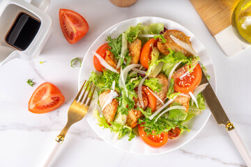 Healthy vegetable green salad with grilled chicken fillet breast, fresh lettuce, tomatoes, onion and balsamic dressing. Spring balanced diet salad on white marble background top view copy space