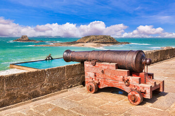 Cannon looking out over the bay at Saint Malo, Brittany, France. Focus on cannon. - obrazy, fototapety, plakaty