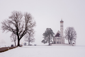 Fototapeta na wymiar Paisaje nevado e iglesia de St. Coloman en Schwangau, Alemania